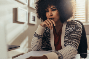 black woman thinking with a pen in her hand