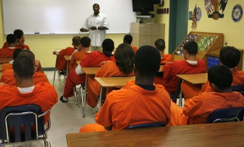 Someone lecturing youths wearing prison clothes