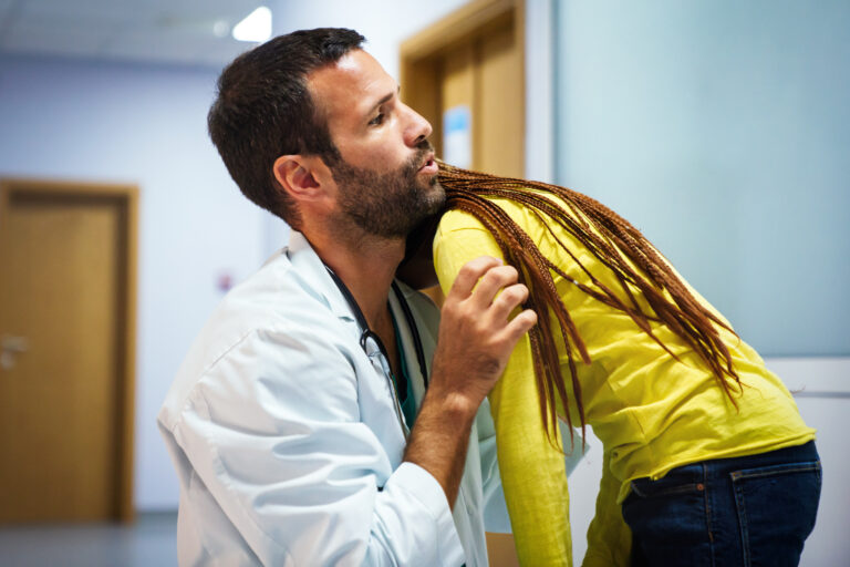 Male doctor having conversation with sad little girl at the hospital. Doctor consoling child