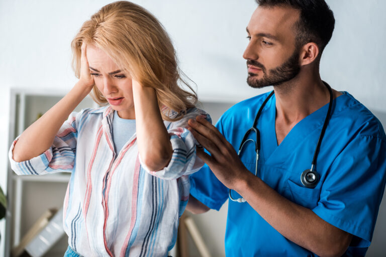 handsome bearded doctor touching emotional woman with headache