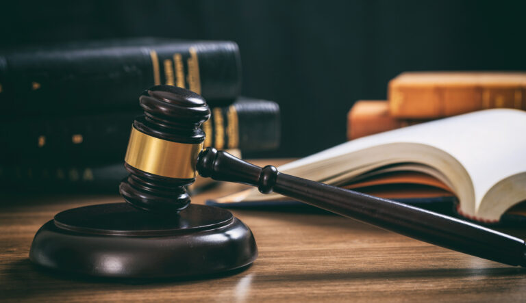 Law gavel on a wooden desk, law books background