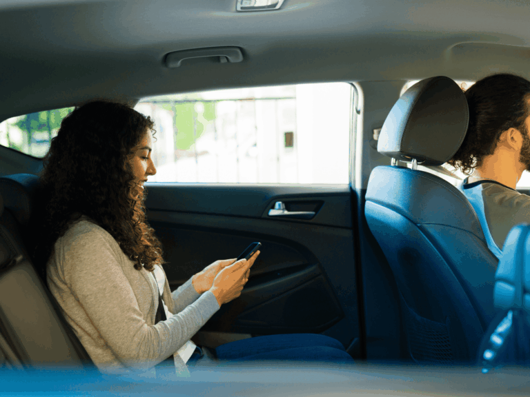 a woman at the backseat of a lyft vehicle, with a male driver