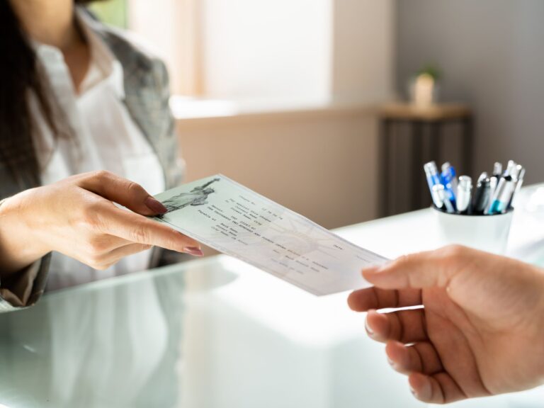A hand passing a check for sex abuse compensation