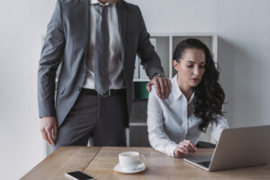 Man in a suit with his hand on the shoulder of a woman leaning over her laptop