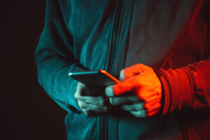 Smartphone in male hands, close up low key image