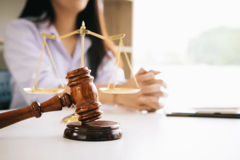 gavel and scales of justice on a desk with a person in the background
