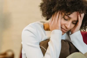 Distressed woman holding her head in her hands, sitting indoors