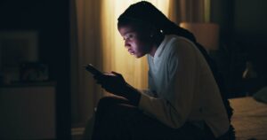 Frustrated girl at night in her home using Snapchat