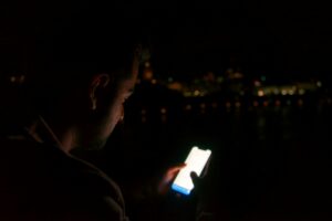 Man in the dark looking at Snapchat on his phone
