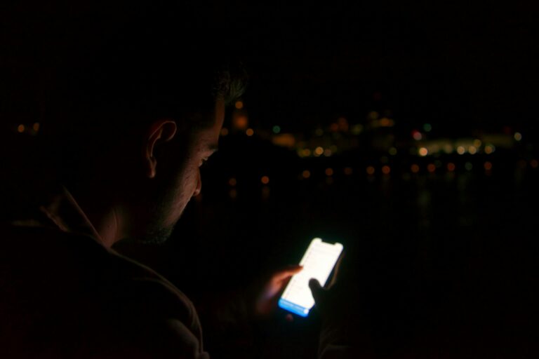 Man in the dark looking at Snapchat on his phone