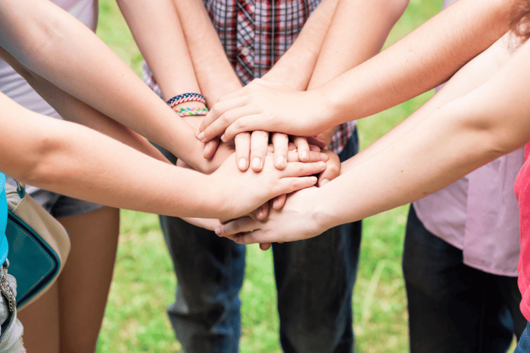 teens hands together during a club meeting