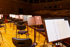 Music books and sheets with musical notation on the stands ready to the concert. Equipment of an orchestra in an arts academy theater setting