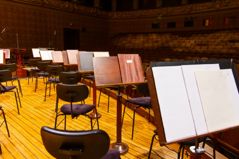 Music books and sheets with musical notation on the stands ready to the concert. Equipment of an orchestra in an arts academy theater setting